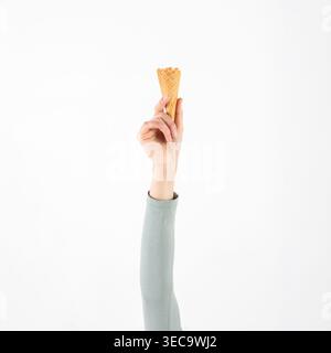 Hand holding an empty waffle ice cream cone against a clean white background Stock Photo