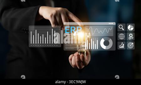 Business professional interacts with digital interface showing ERP software analytics and data visualization concepts with a glowing light bulb repres Stock Photo