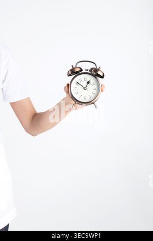 Hand holding a vintage alarm clock symbolizing punctuality and deadlines Stock Photo