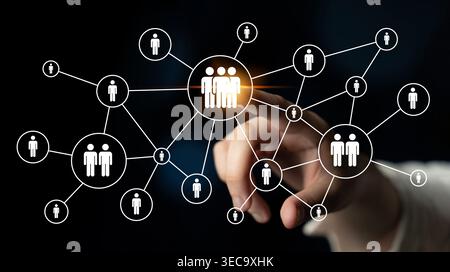 An illustrative image showing a hand pointing at a connected network of people icons on a dark background, symbolizing social interaction and digital Stock Photo