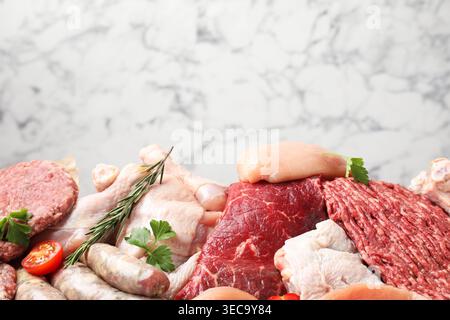 Different raw meat products, tomato and spices against white marble background, closeup Stock Photo