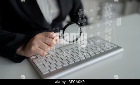 Business professional analyzing data on keyboard with magnifying glass and digital flowchart interface for efficiency enhancement and information tech Stock Photo
