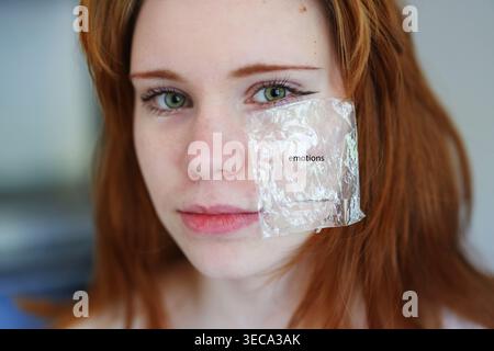 Conceptual closeup of woman with emotion label on face, psychology, sensitivity and modern identity expression. Stock Photo