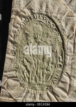 Official seal, archbishop's curia; two seal impressions on a document. Each impression shows a crowned double-headed eagle with a coat of arms in the center. Dry seal impression depicts a clergyman standing in front, holding a crosier in his right hand. 1770, Italy, Genoa., A close-up of a textured, crumpled piece of paper with an embossed oval seal showing a raised figural scene; the paper is mostly off-white and beige with a greenish tint concentrated within the embossed area, and there is a vertical strip of black along the left edge. The embossed oval contains the faint relief of a central Stock Photo