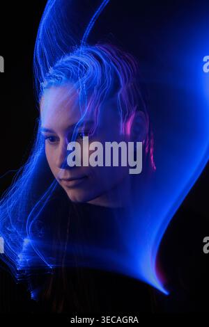 Woman portrait with blue light trails visualizing artificial intelligence, cognition, and neural processing for technology concepts. Stock Photo