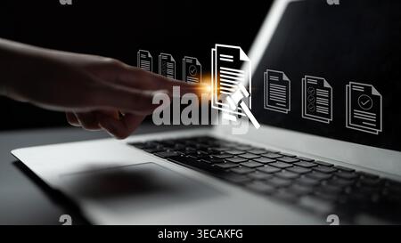 A hand interacts with a laptop screen displaying document management icons. The image captures the essence of digital workflows in a modern workspace Stock Photo