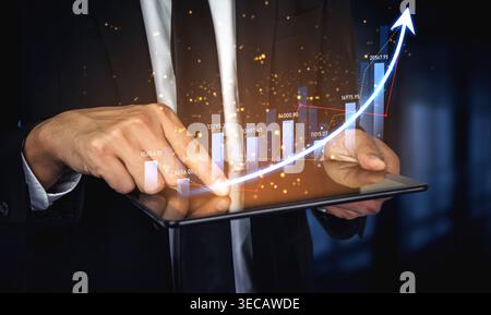 A businessman interacts with a tablet displaying dynamic graphs and trends that symbolize financial growth and success, highlighting modern data analy Stock Photo
