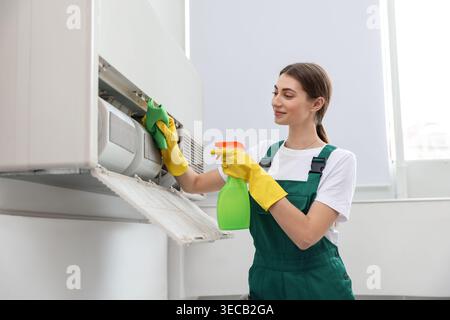 Professional technician cleaning modern air conditioner indoors Stock Photo