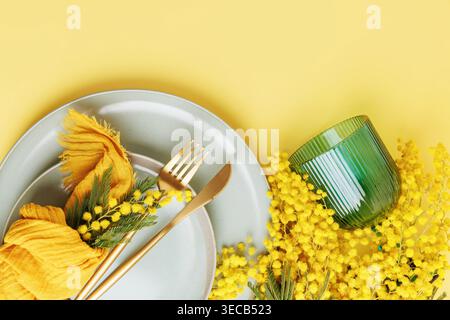 Festive spring composition with mimosa and elegant tableware Stock Photo