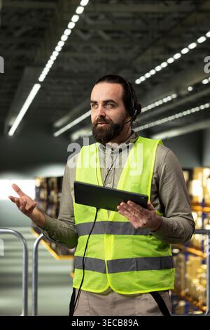 Customer service worker managing phone calls related to shipment tracking and parcel delivery. Man checking logistics and inventory systems, representing large business supply chain operations. Stock Photo
