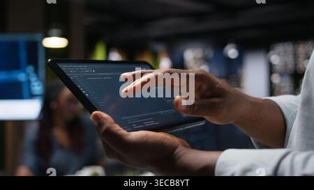 Close up of Silicon Valley company data scientist in office developing apps with device. Employee using deep learning tech on tablet at work to debug applications and resolve issues Stock Photo