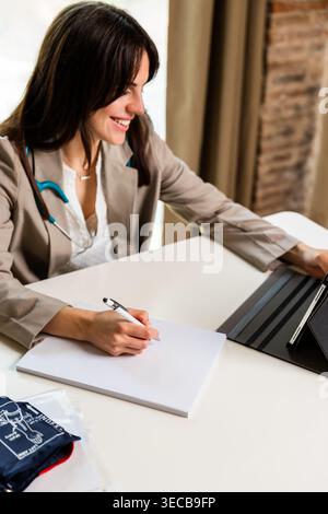 Female doctor consulting, writing notes during healthcare appointment Stock Photo