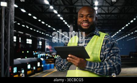 African american technician in workshop handles heavy machinery during production, showing industrial focus and manpower. Manufacturing process with sparks on factory floor. Stock Photo