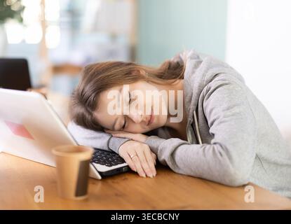 Tired young woman working with laptop Stock Photo