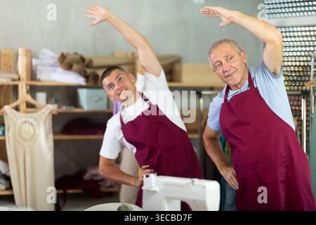 Male tailors doing a warm-up at work Stock Photo