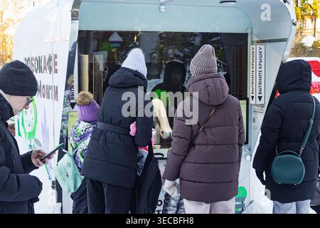 Parkgoers enjoying coffee from an innovative robo-cafe with an automated arm in a snowy winter landscape. Modern technology meets leisure: Russia - Fe Stock Photo