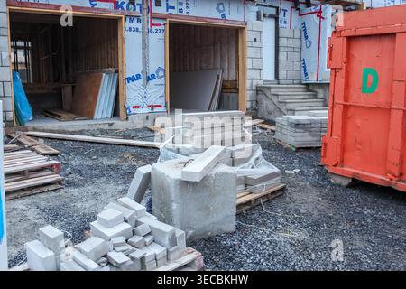 Construction site with stacked concrete blocks, wooden pallets, and an orange storage container in a partially built structure Stock Photo