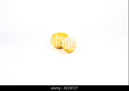 Half sliced lemon leaning against whole lemon on white background Stock Photo