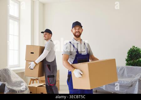 Two men from moving service carrying cardboard boxes with belongings helping clients with relocation Stock Photo