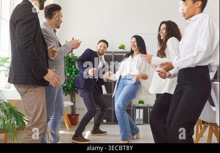 Happy diverse team dancing and celebrating success in office, enjoying fun break and bonding at work Stock Photo