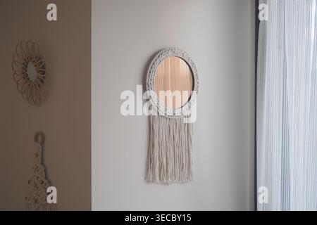 Decorative mirror hangs on wall with fringe design Stock Photo