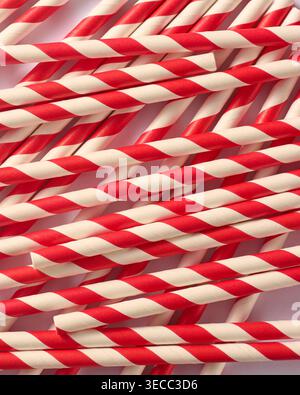 scattered red and white striped paper straws in full frame background, matte finish diagonal patterns in overlapping arrangement, top view Stock Photo