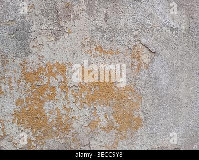 Old concrete wall, damaged, uneven structure, with remnants of yellow paint, vintage background for design Stock Photo