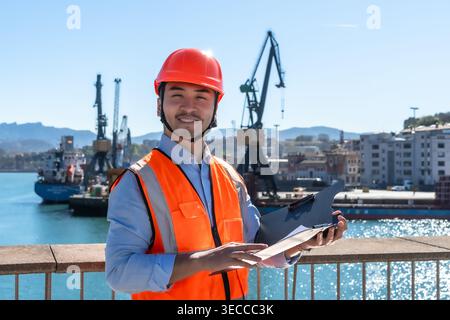 Asian male port worker overseeing cargo operations Stock Photo