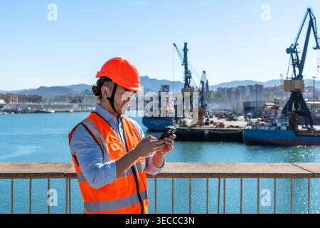 Cargo port worker using smartphone checking logistics Stock Photo