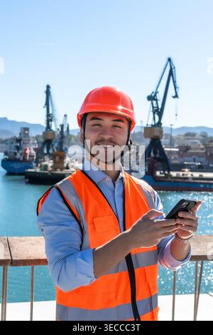 Port worker smiling while using a smartphone Stock Photo