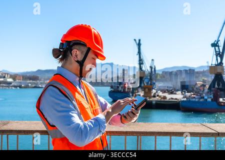 Port engineer working with smartphone managing logistics Stock Photo