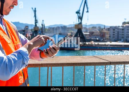 Cargo port worker using tablet managing logistics outdoors Stock Photo
