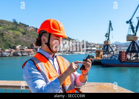 Asian port worker using smartphone checking logistics Stock Photo