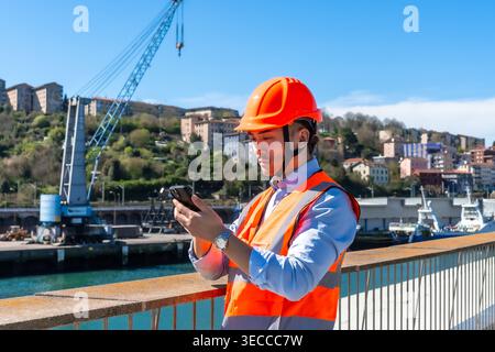 Young engineer using smartphone at cargo port Stock Photo