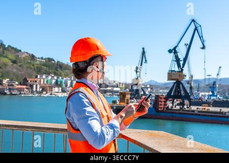 Port worker managing logistics using mobile phone Stock Photo
