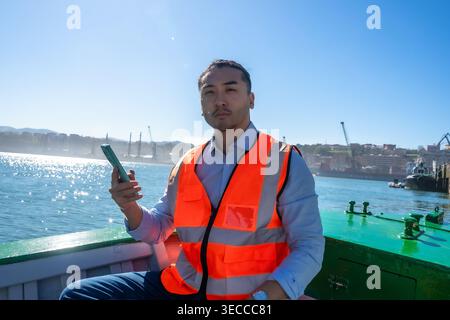 Cargo port worker using smartphone on boat Stock Photo