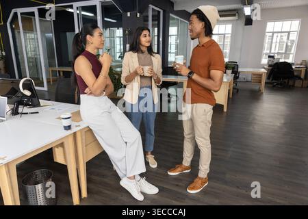 Vertical video: Chatting team holding mugs and cup in open office over coffee, in casual attire Stock Photo