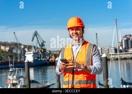 Young asian port worker using smartphone Stock Photo