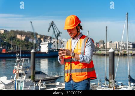 Port worker using smartphone managing logistics and shipping operations Stock Photo