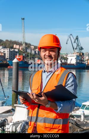 Asian worker holding clipboard at cargo port Stock Photo