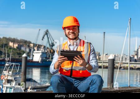 Worker in safety vest using tablet at port Stock Photo