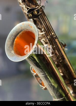 Macro shot of a polished saxophone bell featuring warm orange tones and textured residue. Ideal for music, jazz culture, creativity, and artistic back Stock Photo