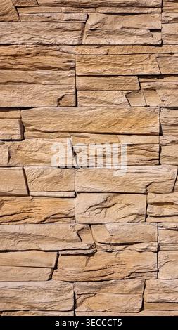 Warm natural stone wall texture with layered beige and brown masonry, rough surface detail and subtle purple accents. High resolution 8K background Stock Photo