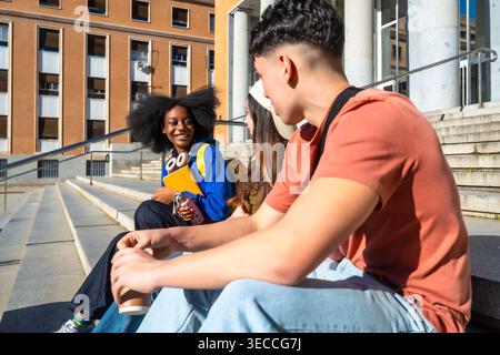 Diverse students talking and laughing on campus steps Stock Photo