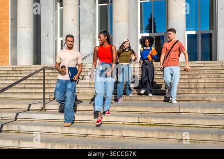 Diverse university students walking down campus stairs after class Stock Photo