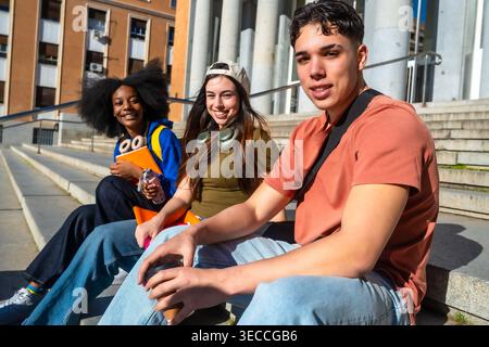 Diverse students smiling sitting on university campus stairs Stock Photo
