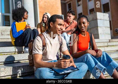 Diverse students sitting on campus steps talking Stock Photo