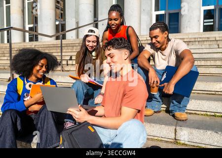 Multiethnic university students sitting on campus steps studying together Stock Photo