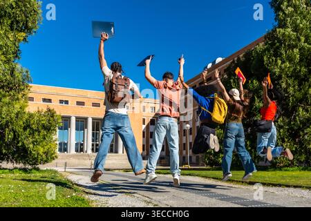 Diverse students jumping celebrating success on university campus Stock Photo