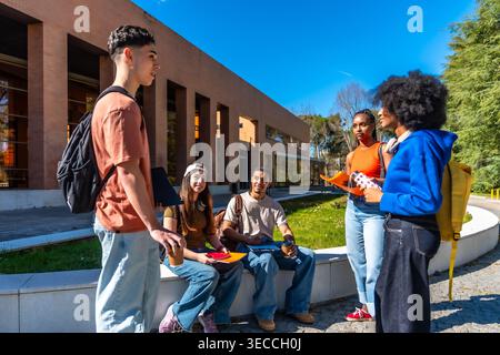 Diverse students conversing on university campus during a sunny day Stock Photo